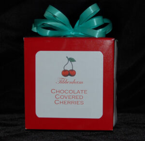 A red box of chocolate covered cherries with a mint green bow