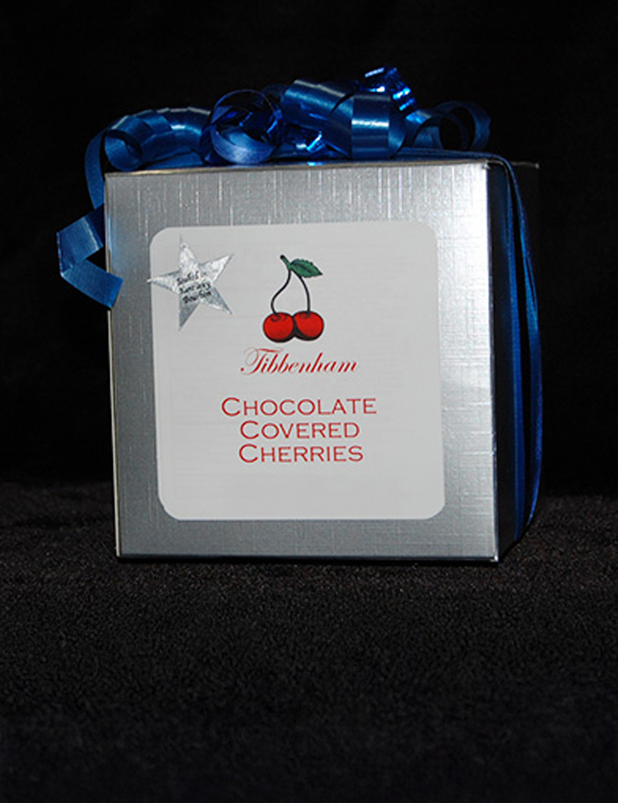 a silver box of chocolate covered cherries with a blue ribbon